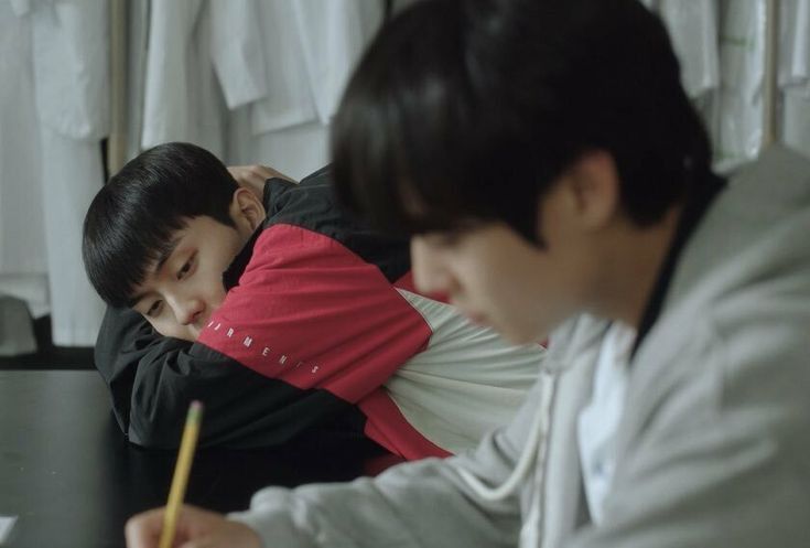 "Su-ho quietly observing Si-eun from his seat - showing his early interest in getting to know the reserved transfer student before they officially became friends. Source: Weak Hero Class 1, Wavve/Netflix"