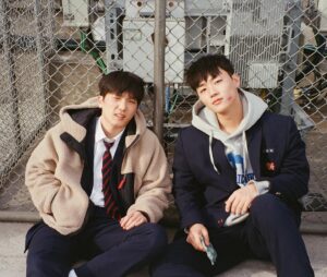 "Screenshot of actors Lee Min-jae and Choi Min-young as Go-tak and Jun-tae sitting side by side on a school rooftop in Weak Hero Class 2, showing their characters' close friendship."